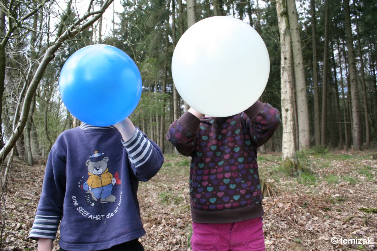 Kinder verstecken sich hinter Luftballons – Foto: Tomizak